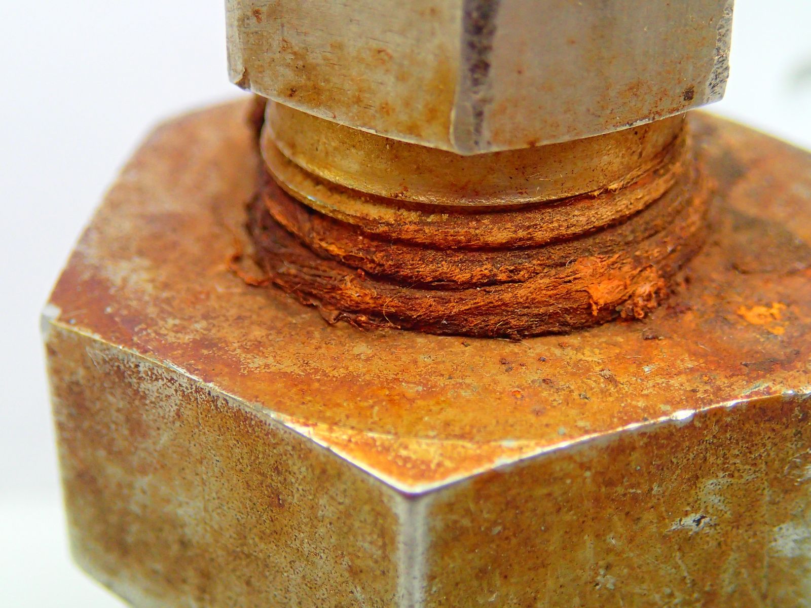 Heavily corroded bolt and nut assembly showing rust layers building up between the mating faces