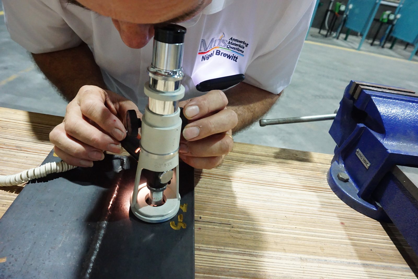 MTIS engineer examining a weld with a portable metallurgical microscope at a workshop bench