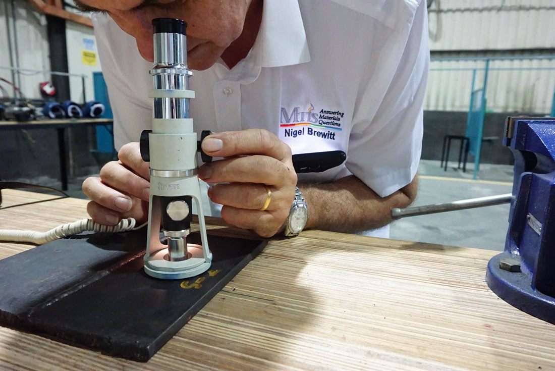 MTIS senior engineer examining a sample under a portable metallurgical microscope
